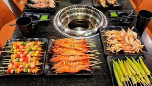 A dining table with various skewers and grilled meats, surrounded by chairs. - Labe Hotel Phu Quoc - Hon Thom Island (Phu Quoc)