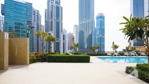 A modern urban setting with high-rise buildings, a swimming pool, and landscaped areas. - 2B With Stunning Burj Views at Burj Crown (Dubai)