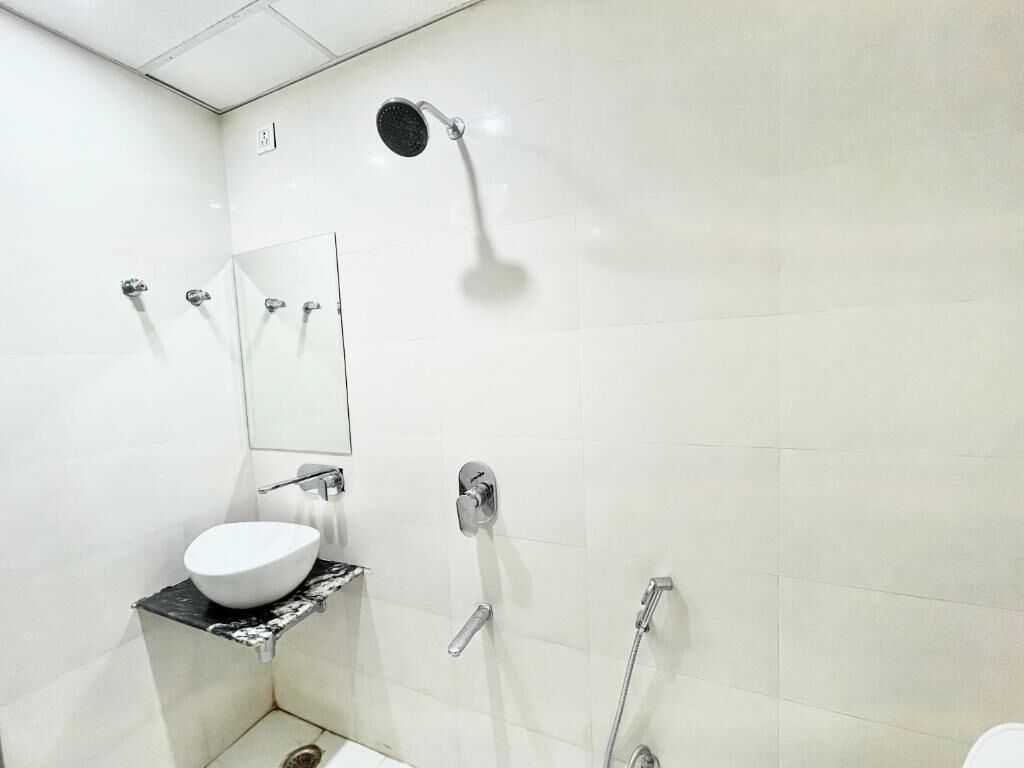 A modern bathroom with a white sink, a mirror, a shower, and a toilet.