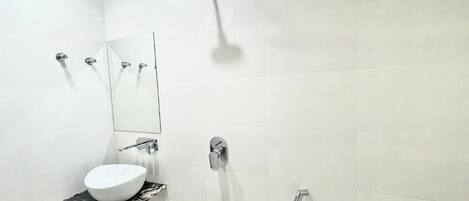 A modern bathroom with a white sink, a mirror, a shower, and a toilet.