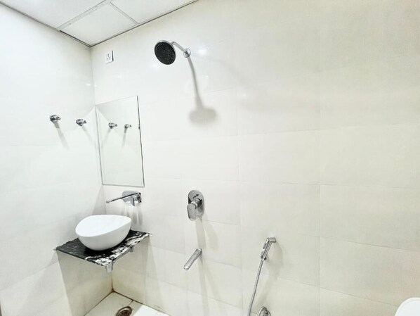 Une salle de bain moderne avec un lavabo blanc, un miroir, une douche et des toilettes.