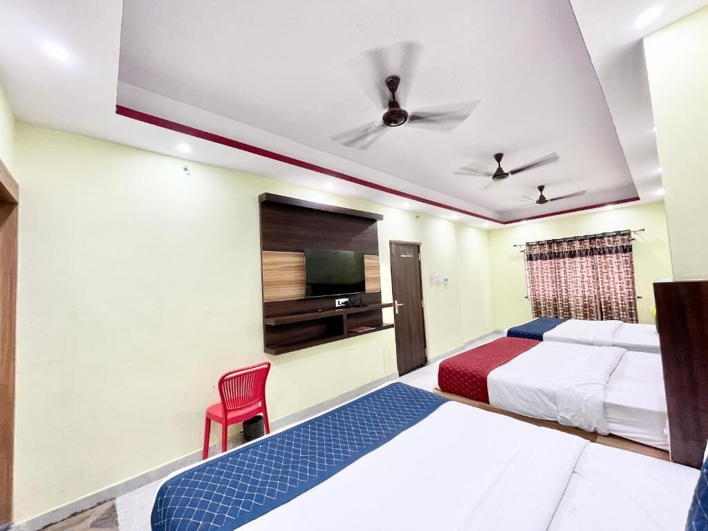 Habitación de hotel con dos camas, un televisor y ventiladores de techo.