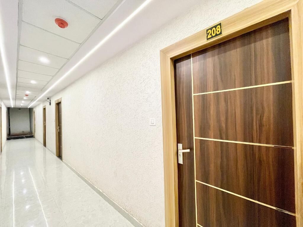 En gang med en dør af træ med skiltet "208" og en hvid væg.