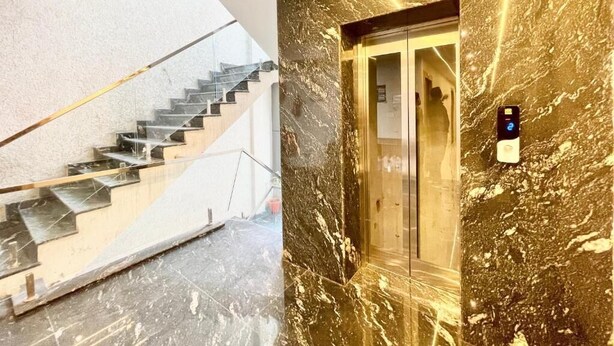 A modern interior with a marble wall, a staircase, and an elevator. - Hotel LV Palace - near Ghats & Temples (Varanasi)