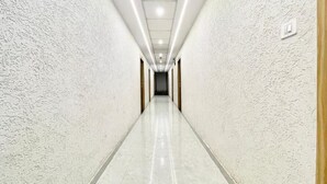 A long, narrow hallway with textured walls and a shiny floor, leading to a door at the end. - Hotel LV Palace - near Ghats & Temples (Varanasi)