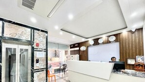 A hotel reception area with a marble floor, a reception desk, a clock, and a wooden panel wall. - Hotel LV Palace - near Ghats & Temples (Varanasi)