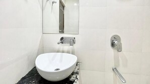 A bathroom with a white sink, a mirror, and a shower. - Hotel LV Palace - near Ghats & Temples (Varanasi)