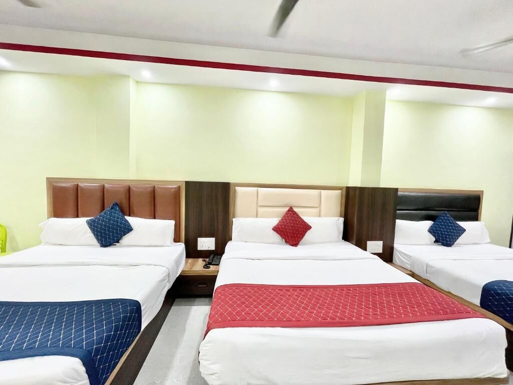 A hotel room with three beds, each with a different colored bedspread.