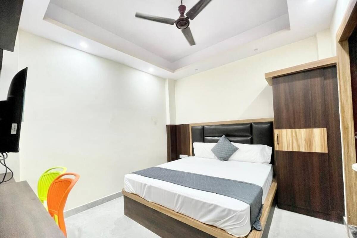 Un dormitorio moderno con una cama, un ventilador de techo, un escritorio y una silla.