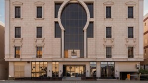 A building with a central arched window, multiple smaller windows, and a paved courtyard. - Jazalah al falah serviced apartments  (Riyadh)