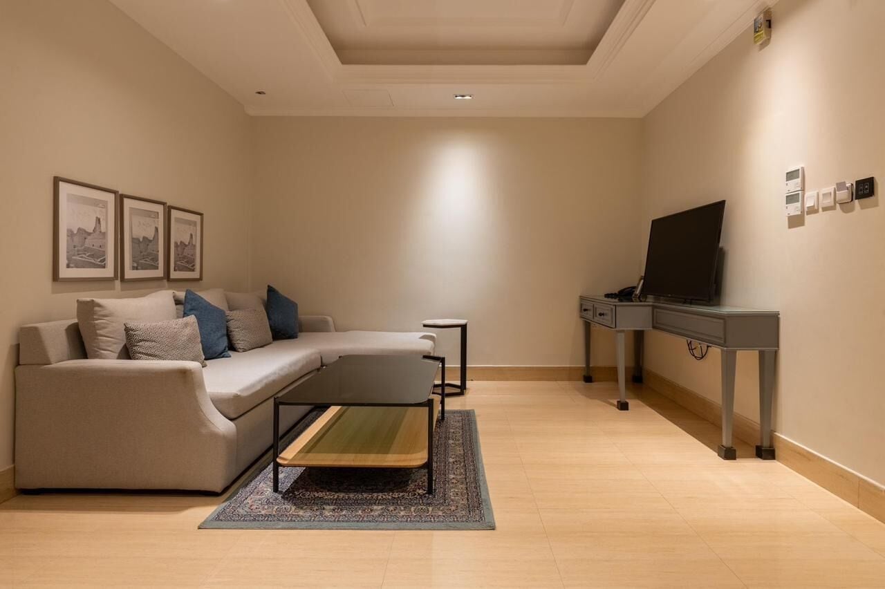 A modern living room with a sectional sofa, a small coffee table, a flat-screen TV, and a side table.