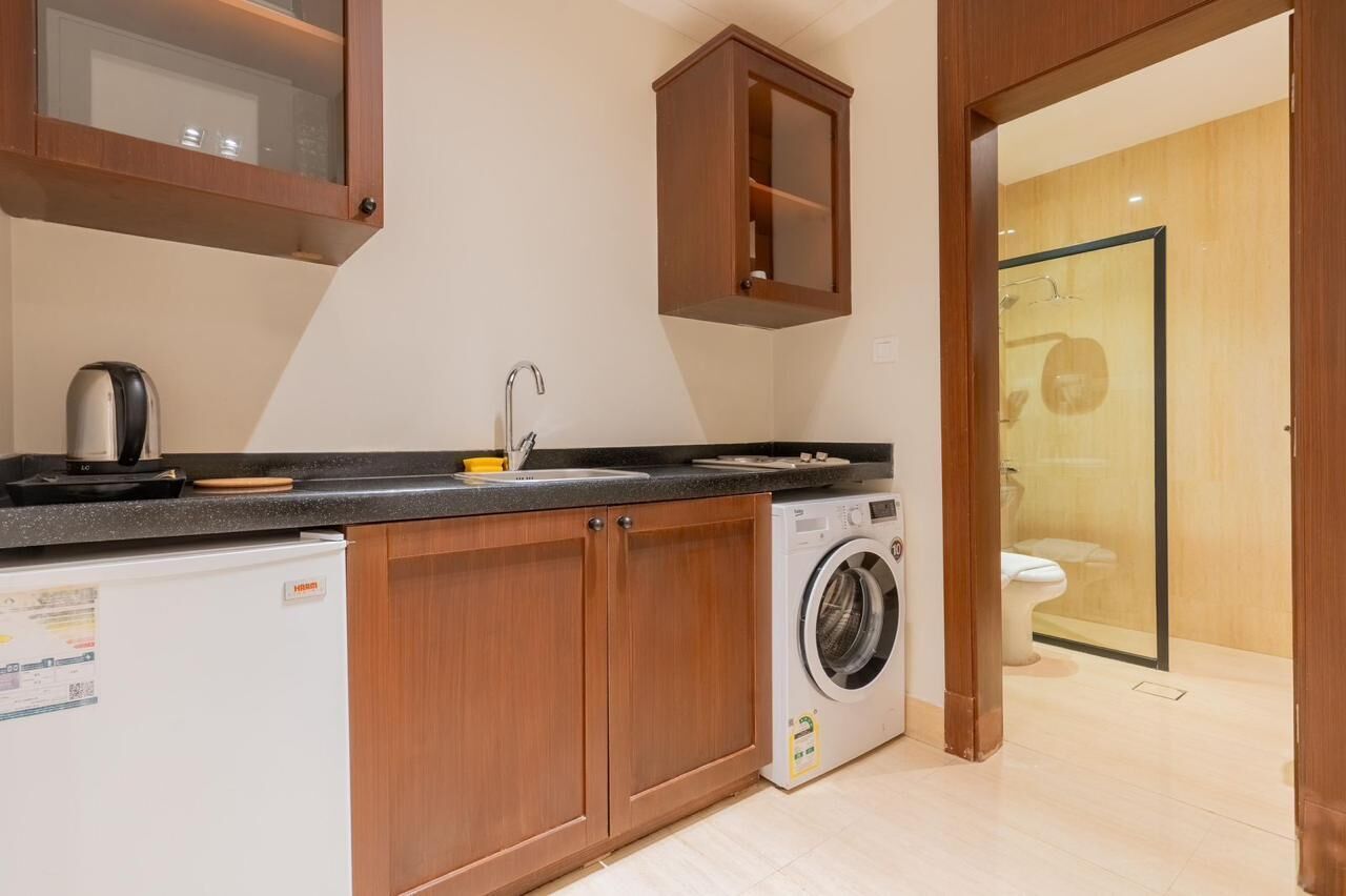 A compact kitchen with a washing machine, a refrigerator, and a cabinet.