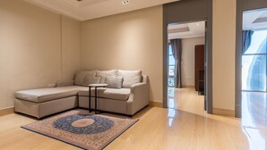 A modern living room with a sectional sofa, a small round table, and a patterned rug. - Jazalah al falah serviced apartments  (Riyadh)