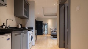 A modern kitchen with built-in appliances, a washing machine, and a dining area with a chair and table. - Jazalah al falah serviced apartments  (Riyadh)