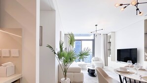 A modern living room with a dining area, a large window, and a view of a cityscape.