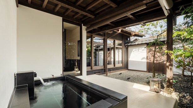A modern indoor garden with a water feature, stone seating, and a traditional Japanese-style entrance.