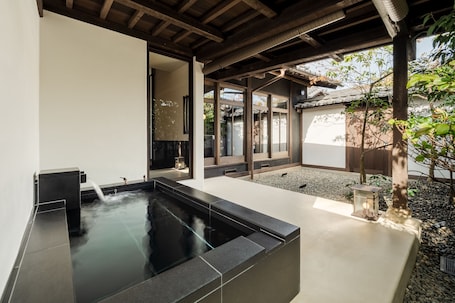 A modern indoor garden with a water feature, stone seating, and a traditional Japanese-style entrance.