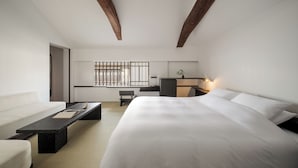 A modern hotel room with a large bed, a desk, and a seating area.