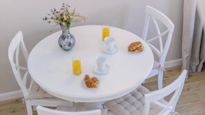 A round white table with a vase of flowers, two glasses of orange juice, a croissant, and a plate of croissants. - Cavtat Cozy Retreat Close to Beach (Konavle)
