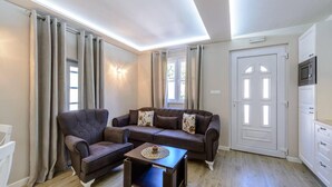 A living room with a dark brown sofa set, a coffee table, and a white door with a built-in microwave. - Cavtat Cozy Retreat Close to Beach (Konavle)