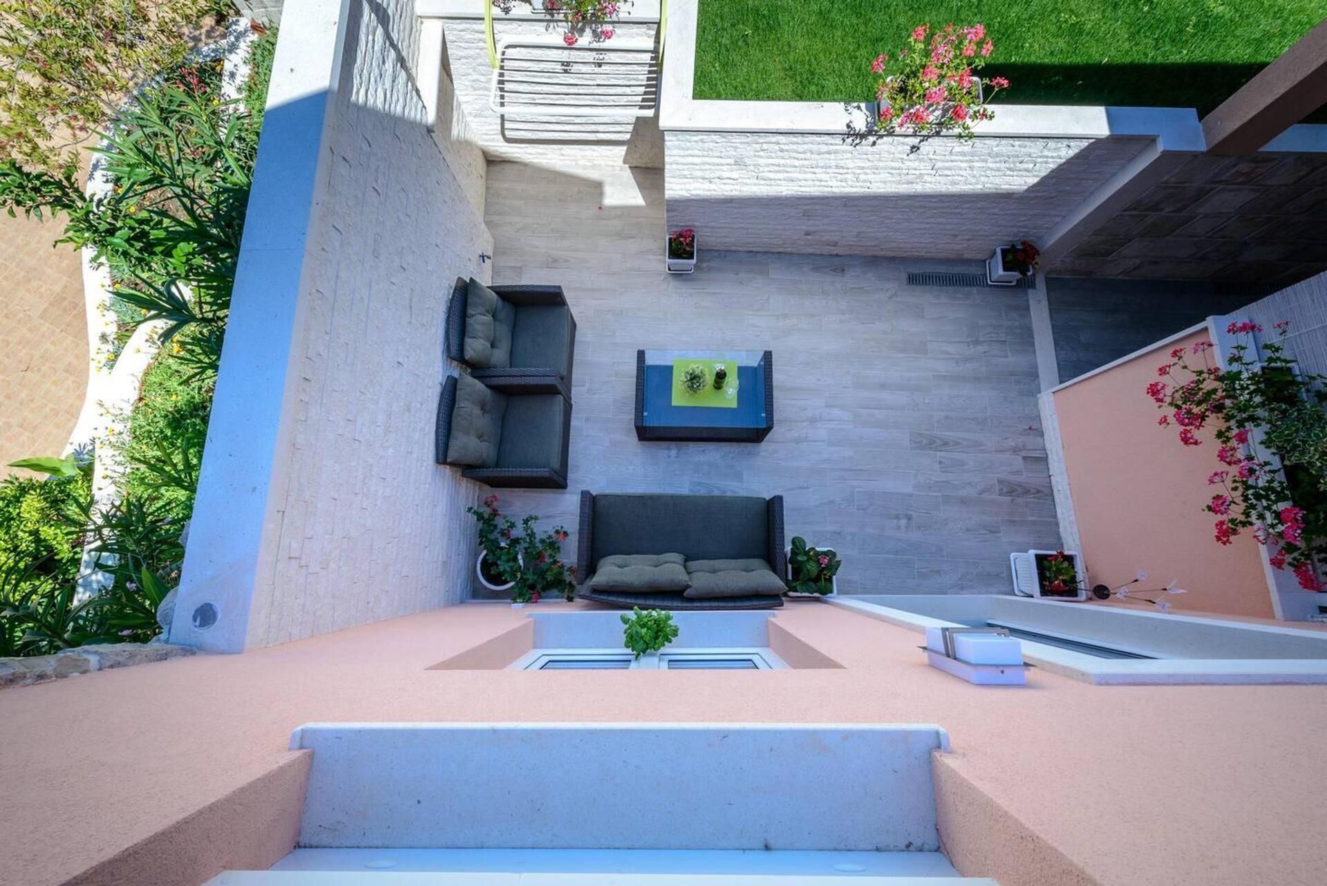 Un patio moderno al aire libre con una zona de estar integrada, una pequeña mesa y plantas en macetas.