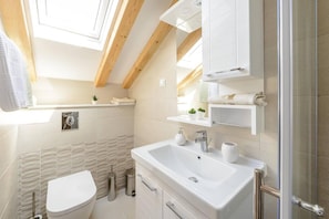 Een moderne badkamer met een groot wastafel, toilet en douchegedeelte.