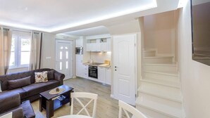 A compact living space with a sofa, coffee table, and a dining area. A kitchen with white cabinets and a microwave is visible. - Cavtat Cozy Retreat Close to Beach (Konavle)