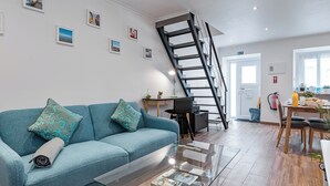 Ein modernes Wohnzimmer mit einem blauen Sofa, einem Glastisch und einer Treppe.