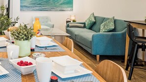 Ein modernes Wohnzimmer mit Essbereich, einem großen Gemälde von einer Welle an der Wand und einem grünen Sofa.