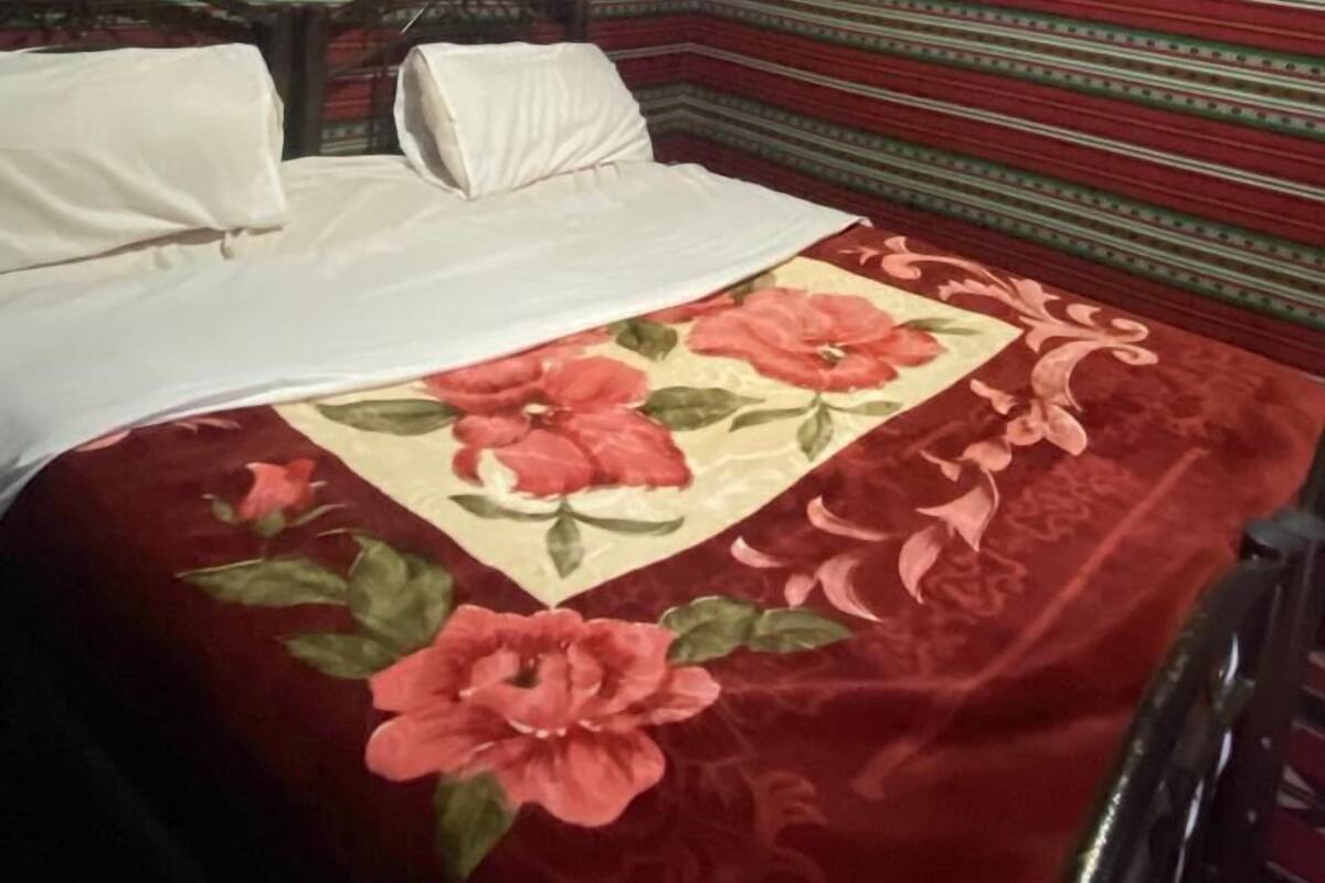 A room with a striped ceiling, a bed with a floral bedspread, and a headboard.
