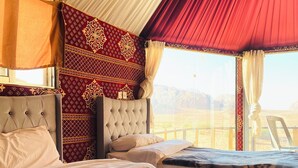 Une chambre à coucher avec un grand lit, une tête de lit capitonnée et une vue sur l’extérieur.