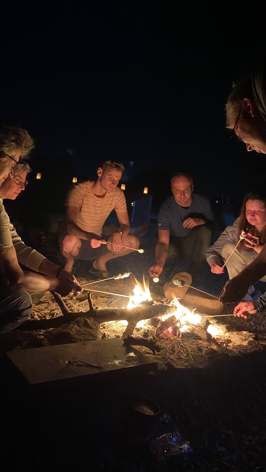 Un groupe de personnes s’est rassemblé autour d’un feu de camp au coucher du soleil.