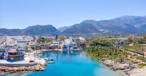 Un pueblo costero con un puerto deportivo, edificios y montañas al fondo.