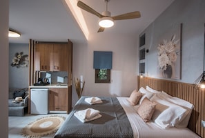 A modern bedroom with a bed, bedside table, and a view of the kitchen.