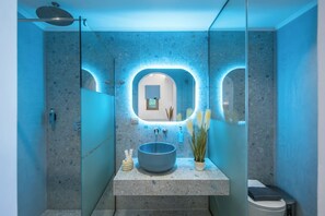 Un bagno moderno con un grande specchio, un lavabo rotondo e una zona doccia.