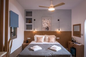 Habitación de hotel con cama, ventilador de techo, obra de arte en la pared y escritorio con silla.