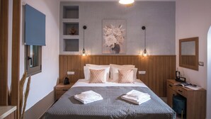 Une chambre à coucher comprenant un lit, des tables de chevet, un ventilateur de plafond, une étagère fixée au mur, un tableau et un miroir.