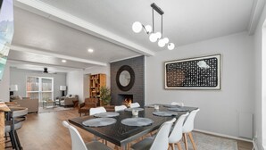 A modern dining area with a dark wooden table, white chairs, and a fireplace. - Spacious Retreat 8 Bedroom River (Bethany)