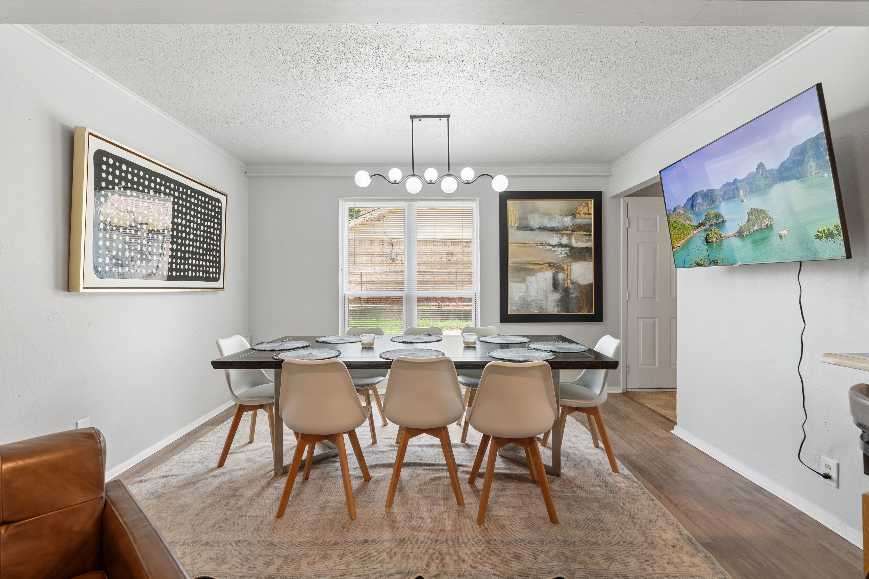 A dining area with a large table, four chairs, and a modern chandelier.