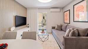 A modern living room with a flat-screen TV, a sofa, and a dining area with a table and chairs. - HaHavatselet 19 - Isrentals - Superior 5 (Jerusalem)