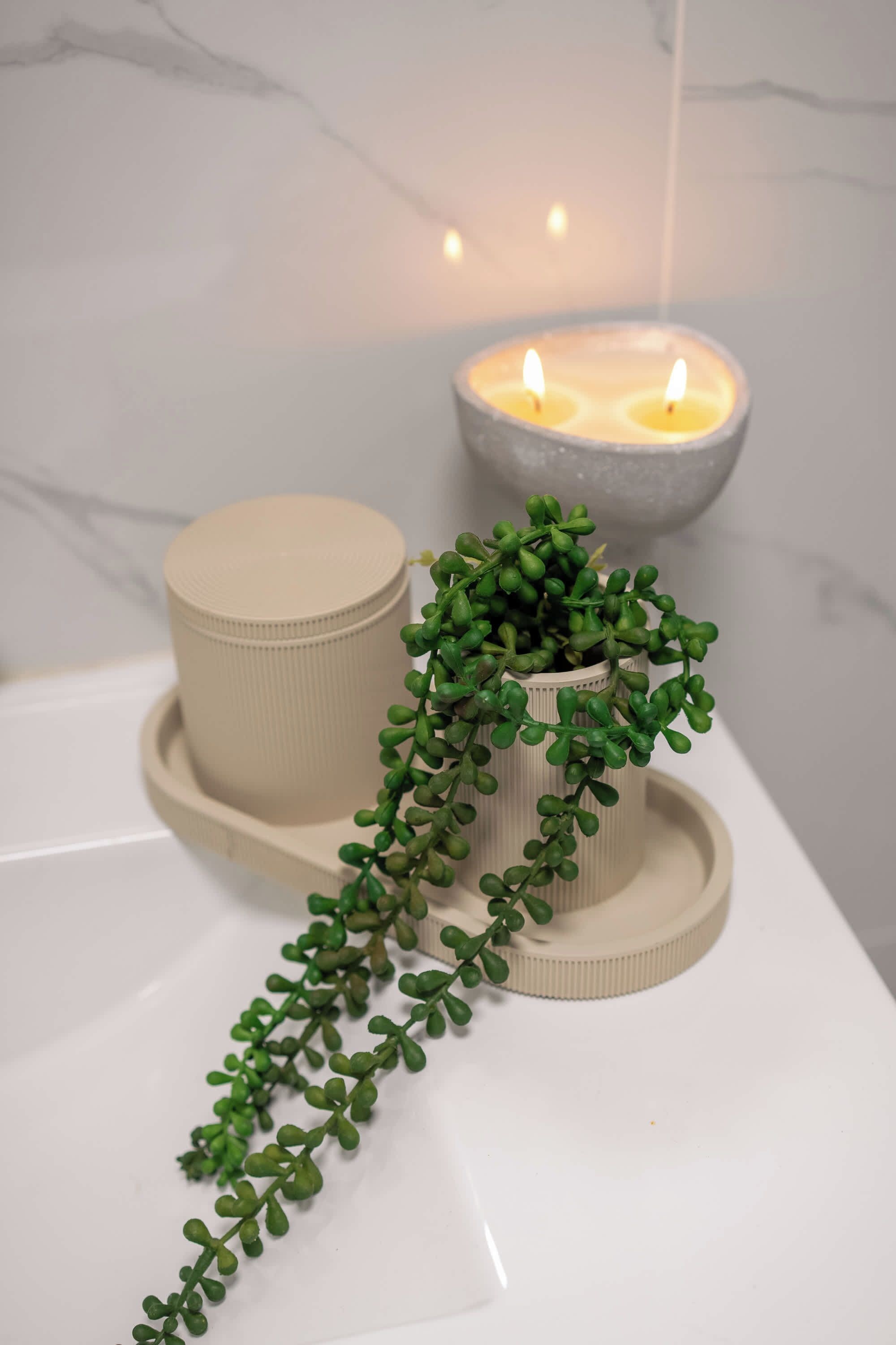 A bathroom with a white bathtub, a beige candle holder, and a small potted plant.
