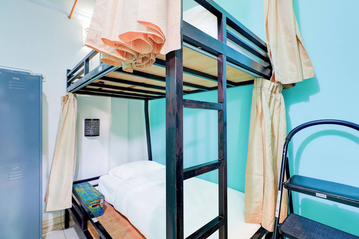A bunk bed room with a blue wardrobe, a small table, and a chair.