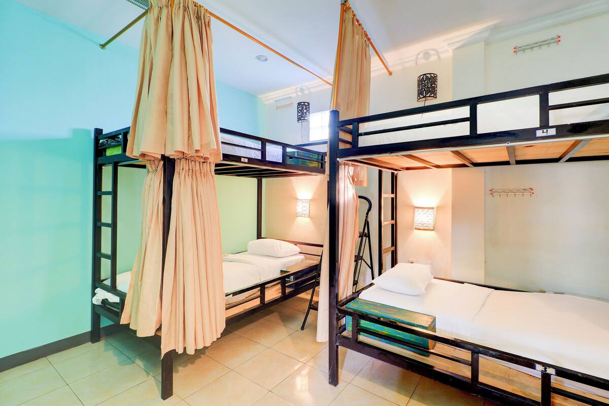 A room with bunk beds, a hanging curtain, and a wall-mounted light fixture.