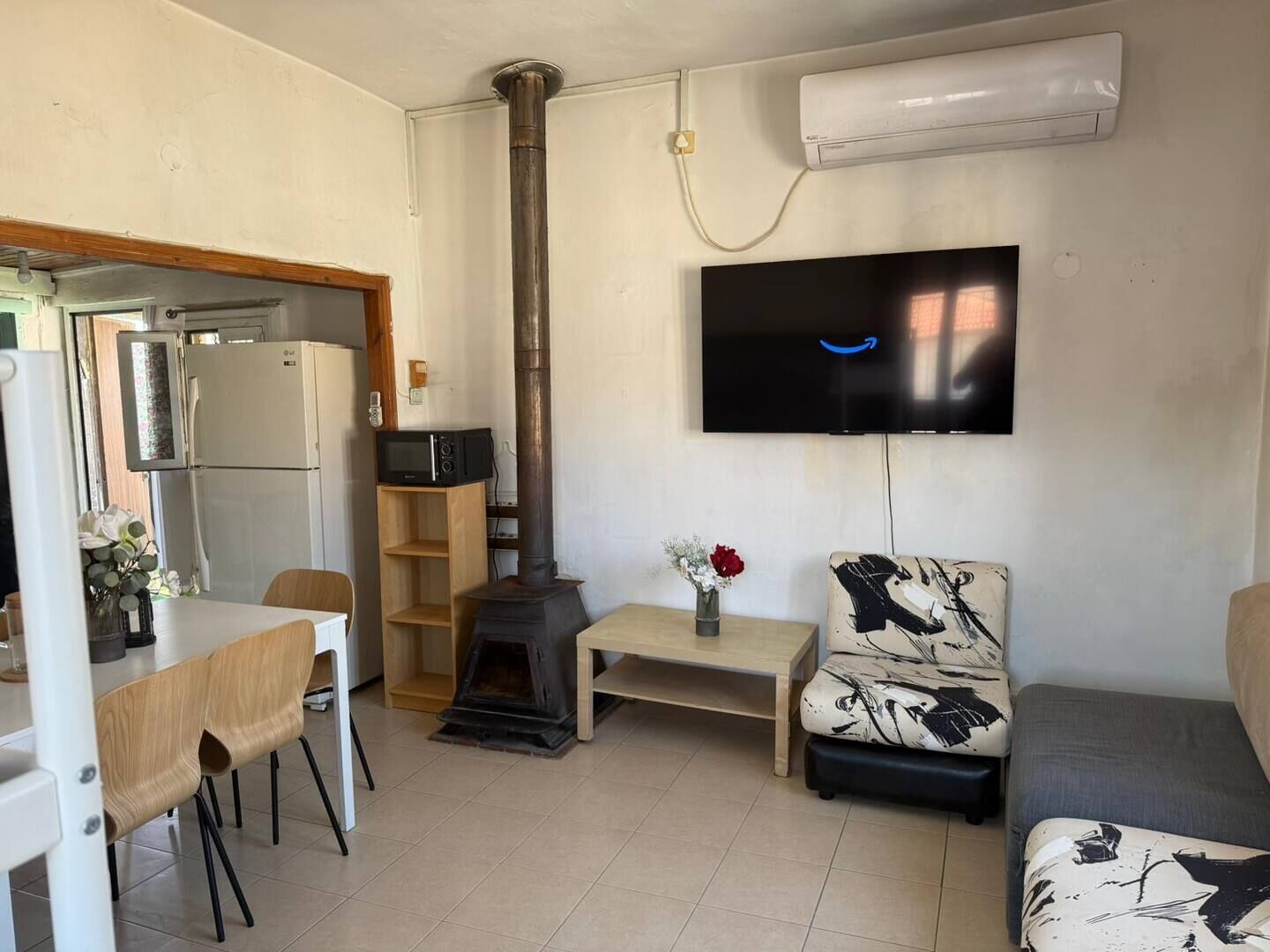 Una sala de estar con televisor, chimenea, comedor y cocina visible a través de una puerta abierta.