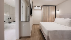 A modern bedroom with a large bed, a mirror, a TV, and an air conditioning unit. - baraca boutique (Jerusalem)