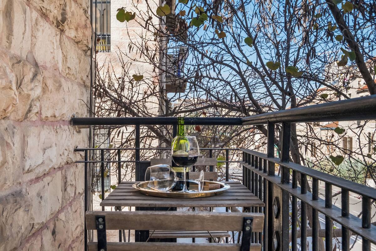 Varanda com mesa posta para dois, com uma garrafa de vinho e copos.