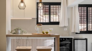 A modern kitchen with a wooden island, two pendant lights, a refrigerator, and a stove. - baraca boutique (Jerusalem)