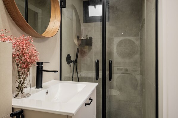 A modern bathroom with a white sink, black faucet, and a glass shower enclosure. - baraca boutique (Jerusalem)
