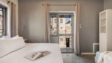 Ein Schlafzimmer mit einem Bett, einem Fenster, einer Tür zu einem Balkon und einem weißen Kleiderschrank.