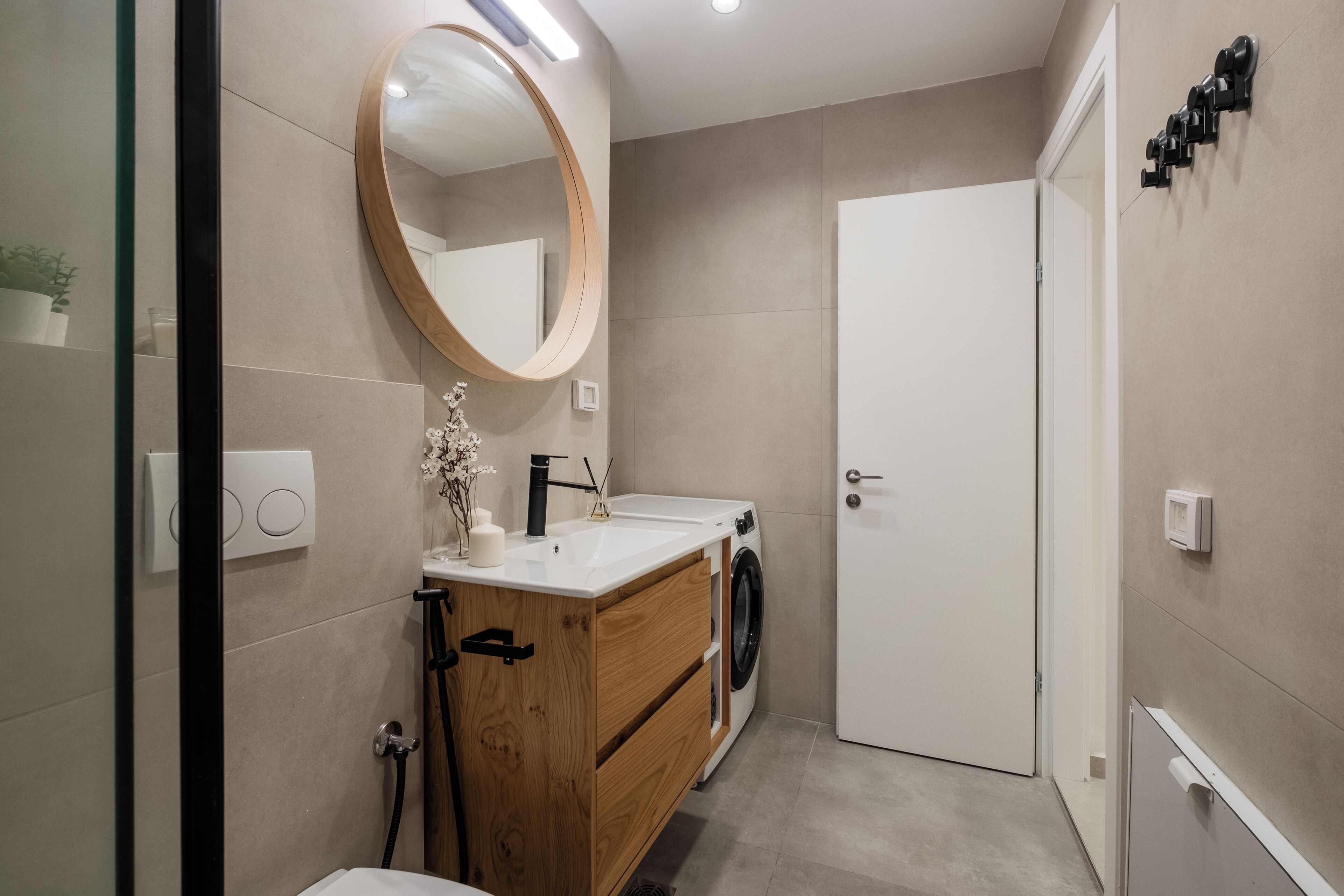 Ein modernes Badezimmer mit einem Holzbadezimmer-Möbelstück, einer Waschmaschine und einem großen Spiegel.